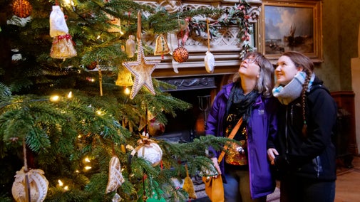 Visitors exploring the festive house and enjoying the Christmas tree decorations at Tyntesfield near Bristol.